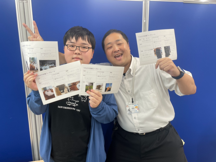 ペットについてまとめたプリントをもって生徒とコーチが仲良く笑っている様子