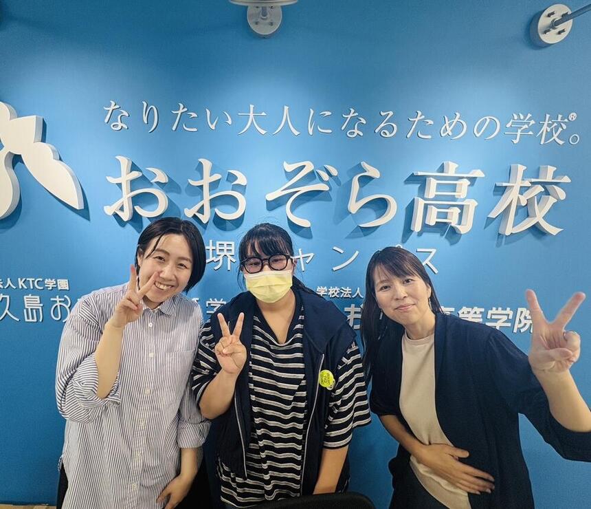 2人のコーチに囲まれたYさんが笑顔でピースしている写真