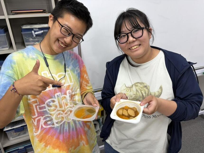 子ども・福祉コースに在籍する生徒が試食前の介護食を持って笑顔で写真に写っている様子