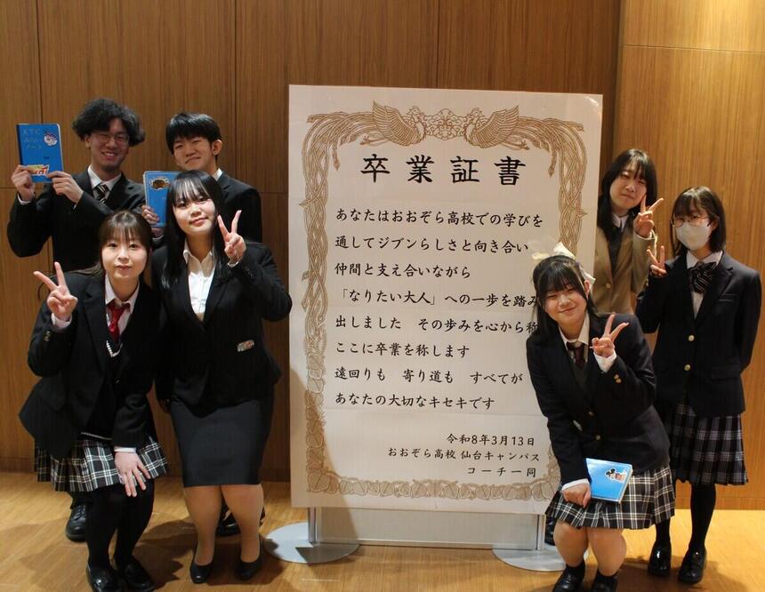 卒業証書パネルの前で仲間とともに