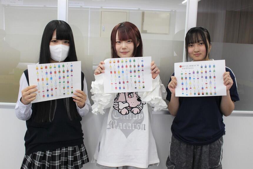 みらいの架け橋レッスン「トータルビューティ（カラーセラピー）」に参加した1年次生3人が笑顔でカラーボトルの表を持っている様子
