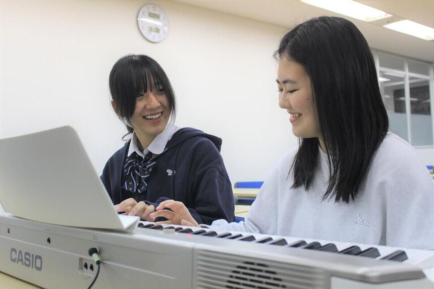 子ども・福祉コース在籍の女子生徒2人が、ピアノを弾きながら笑顔で話している様子