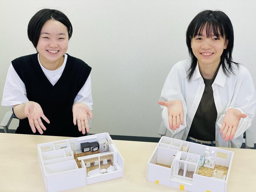 住環境デザインコースの生徒2人が、自分で作成した模型と一緒に写真に写る様子。
