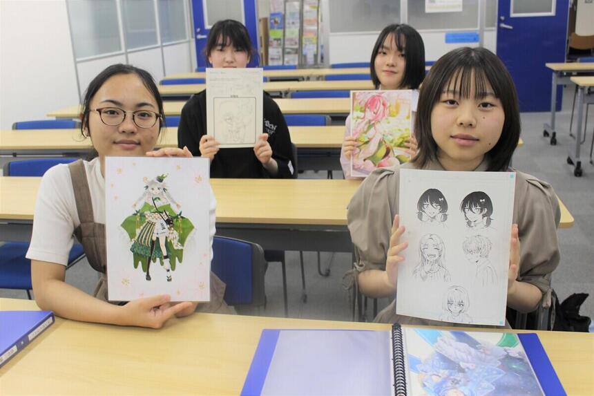 マンガイラストコース生徒4名が、自分で描いた作品を手に持ち写真に映る様子