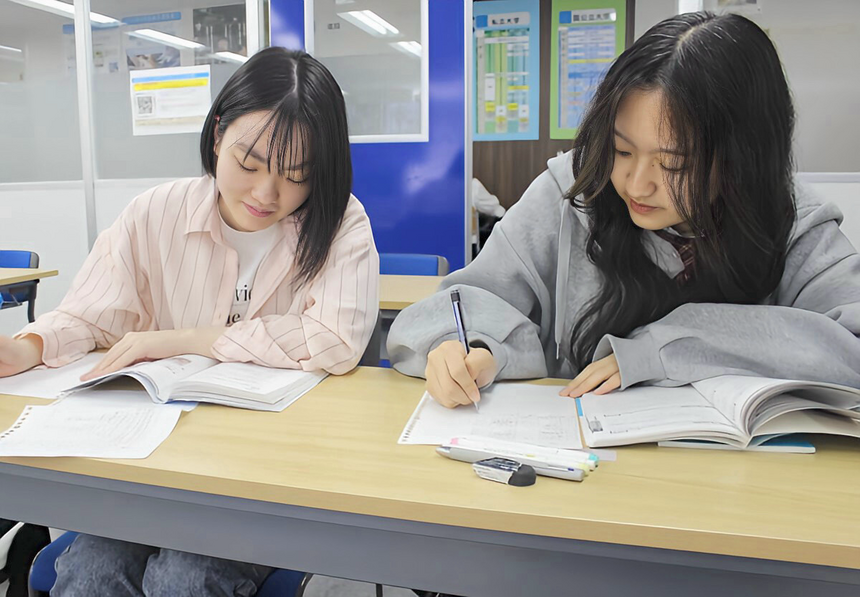 仙台キャンパスの教室で、女子生徒2人が検定取得に向けて真剣に学習している様子。