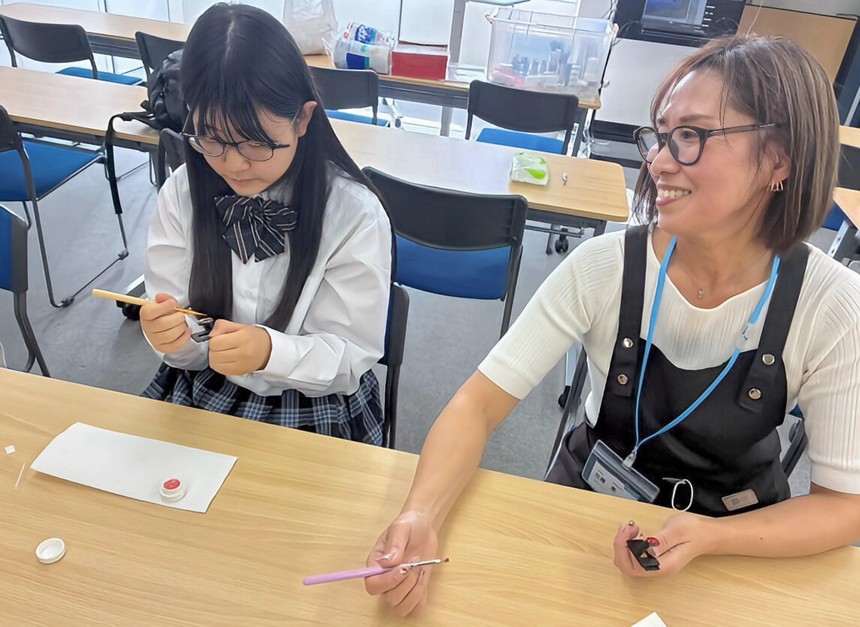 仙台キャンパスの教室で、プロのネイリスト講師が生徒と一緒にネイルを楽しむ様子。