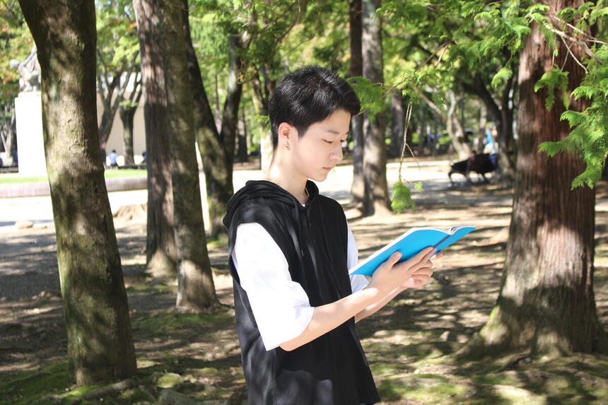 緑豊かな公園で、生徒がKTCみらいノート®を開いて真剣に見つめている様子