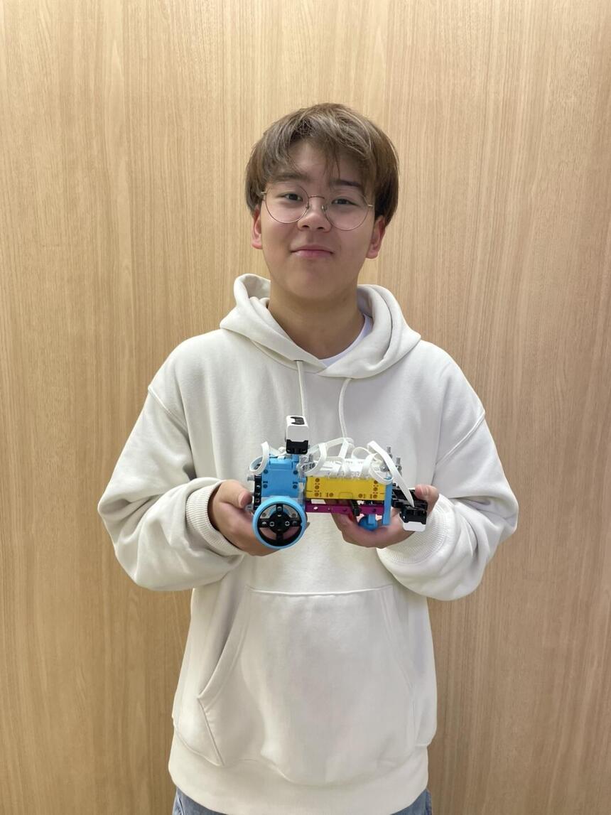 ロボットプログラミング教材を持って笑顔の男子高校生