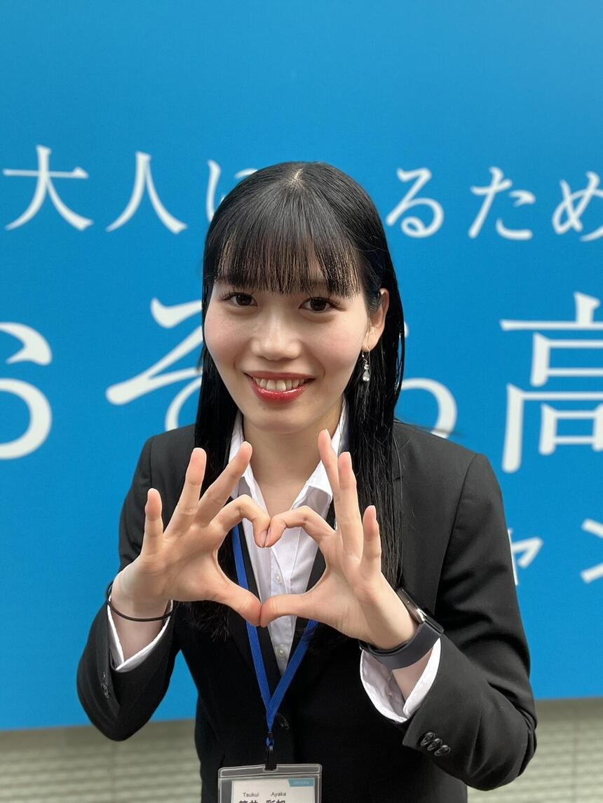 コーチが笑顔で手にハートをつくっている写真