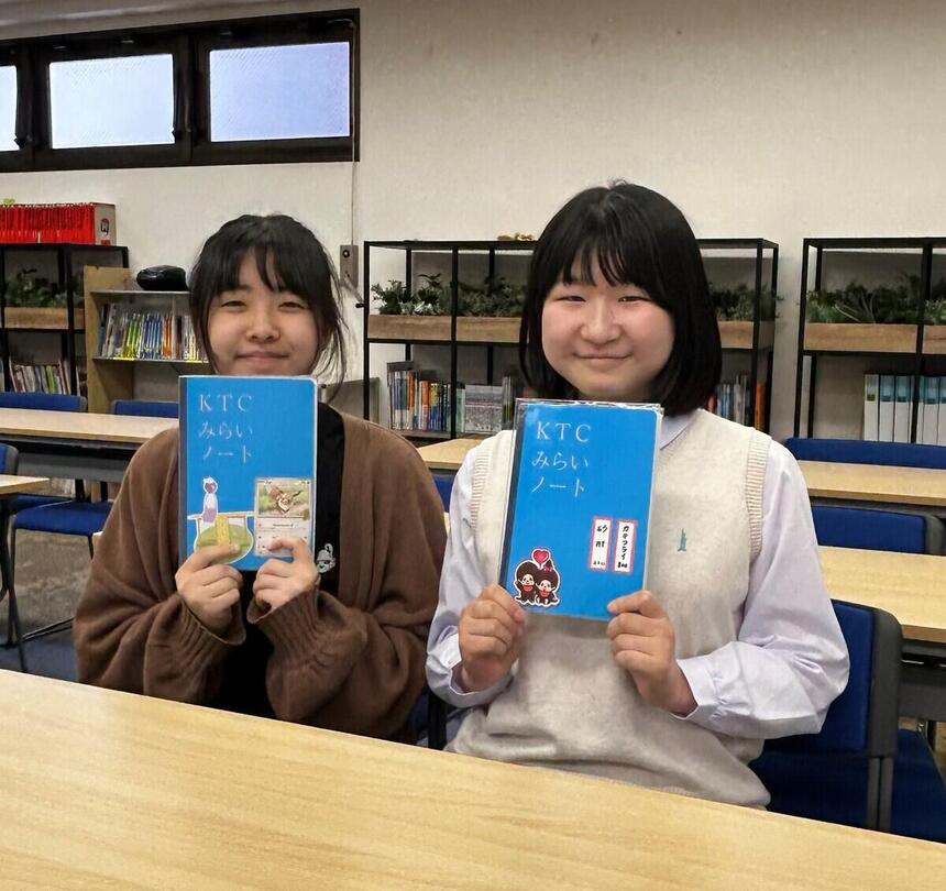 教室で、インタビューに答えた1年生2人がみらいノート®を見せている様子