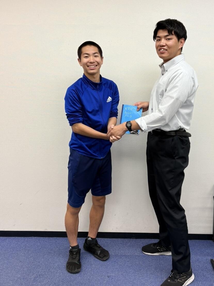 高校2年生の男子生徒とマイコーチ®がみらいノート®を中心に握手をしている。