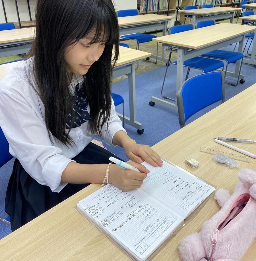 生徒がマーカーを持って、机に向かっている様子の写真