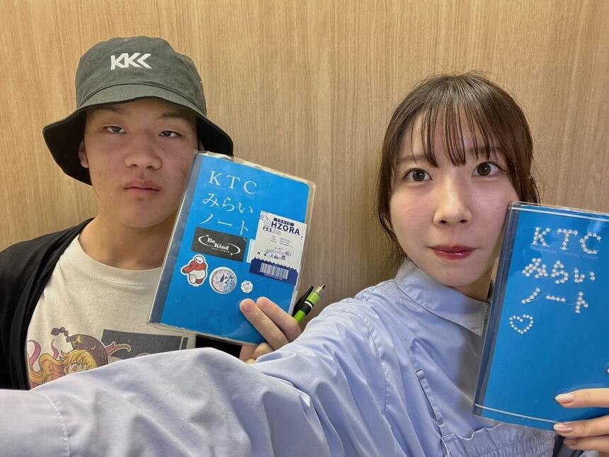 男子生徒とコーチがみらいノート®を持ってそれぞれの表紙を見せている写真