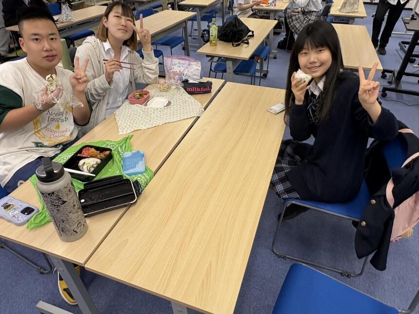 高校生の男女3人が集まって昼食を楽しんでいる。