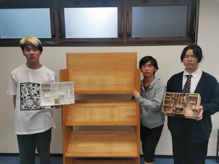表彰棚の付近で部屋のデザイン模型と一緒にポーズをきめている住環境デザインコース生徒達のインタビュー写真