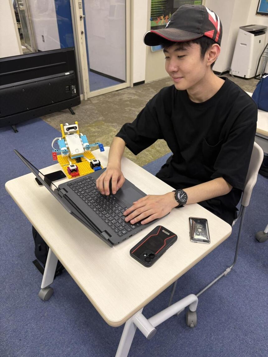 男子高校生が、ロボットのプログラムを作るためにパソコンを操作している。