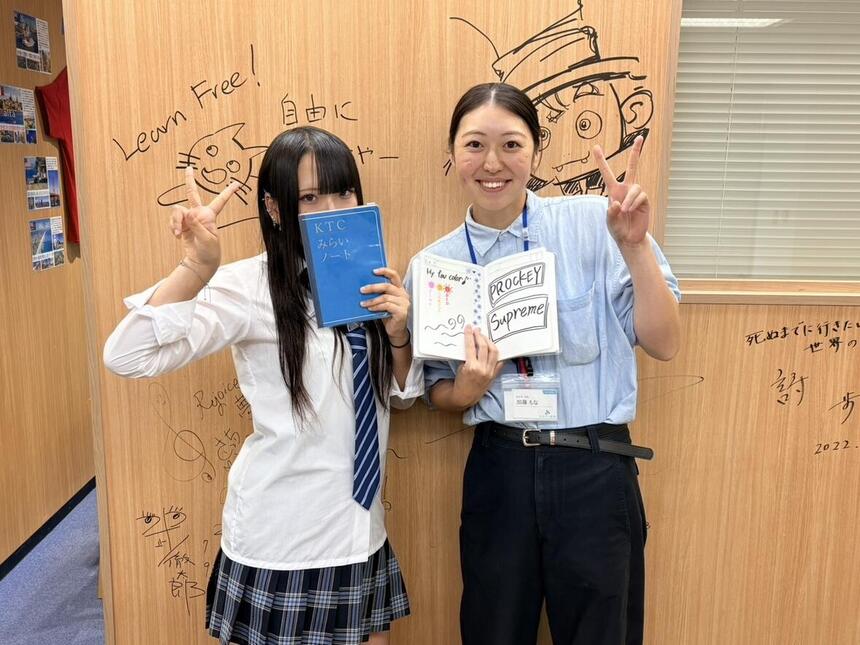 生徒とコーチが片手でピースをし、反対の手にはみらいノートを持って笑顔で並んでいる。