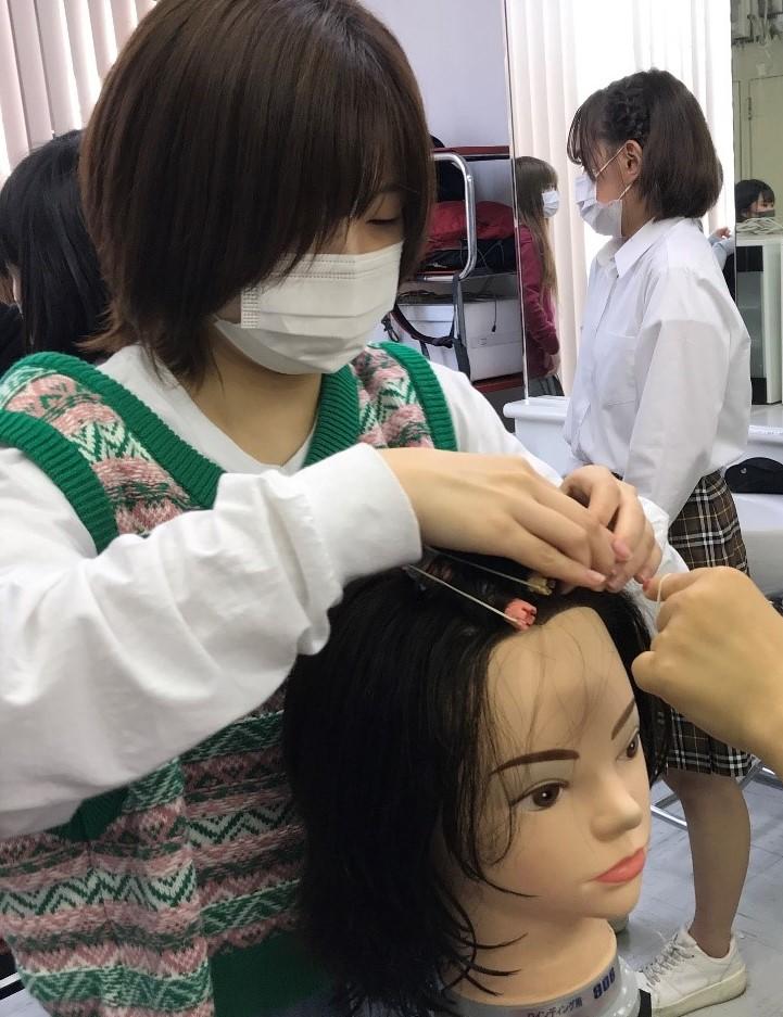 マネキンの頭を使ってヘアメイクを練習するおおぞら生