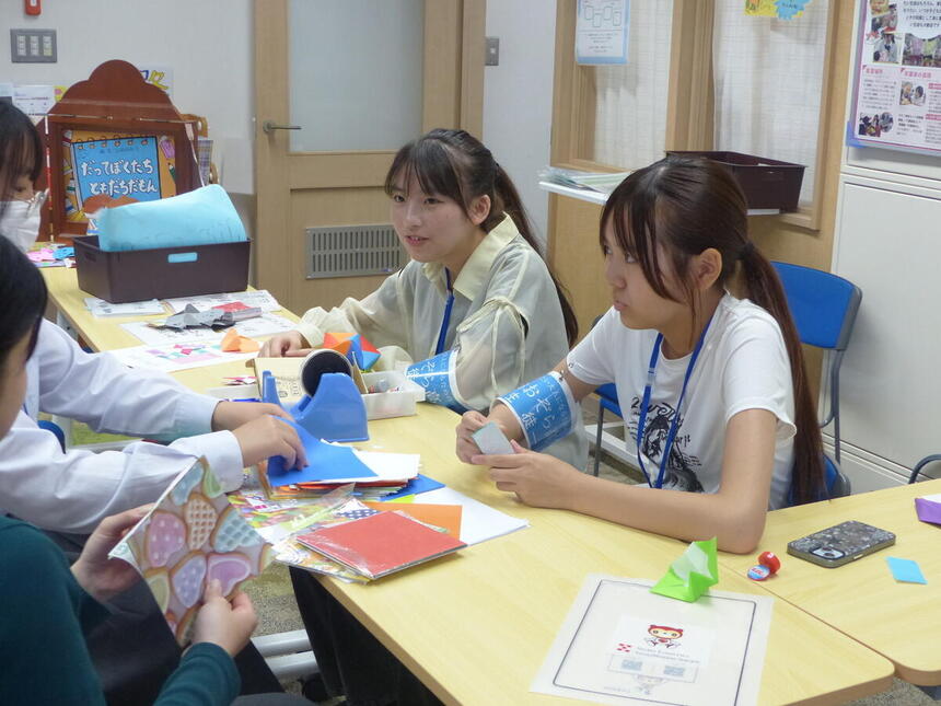 オープンキャンパスで、子ども・福祉コースの生徒が、体験に来た生徒へ折り紙を教えている様子