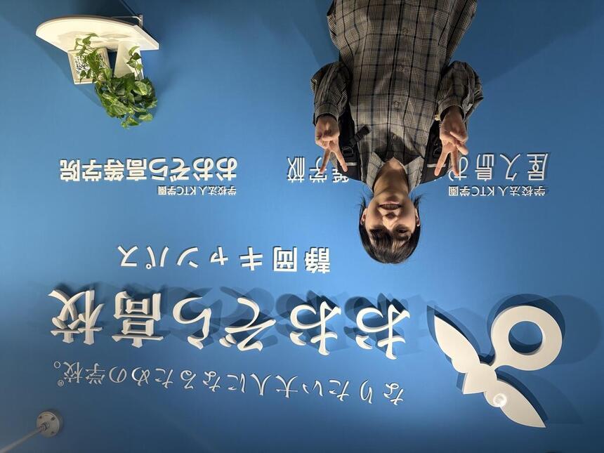 キャンパスの入り口で生徒がピースしている写真