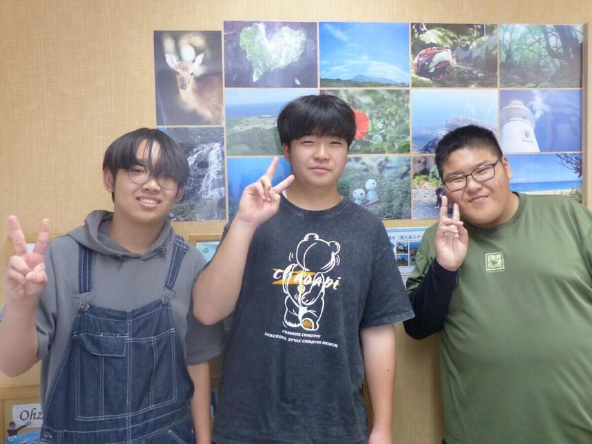 屋久島の写真の前で在校生3人の写真