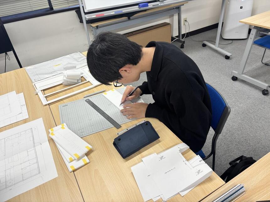 教室でスチレンボードをカッターを使って切り出している生徒