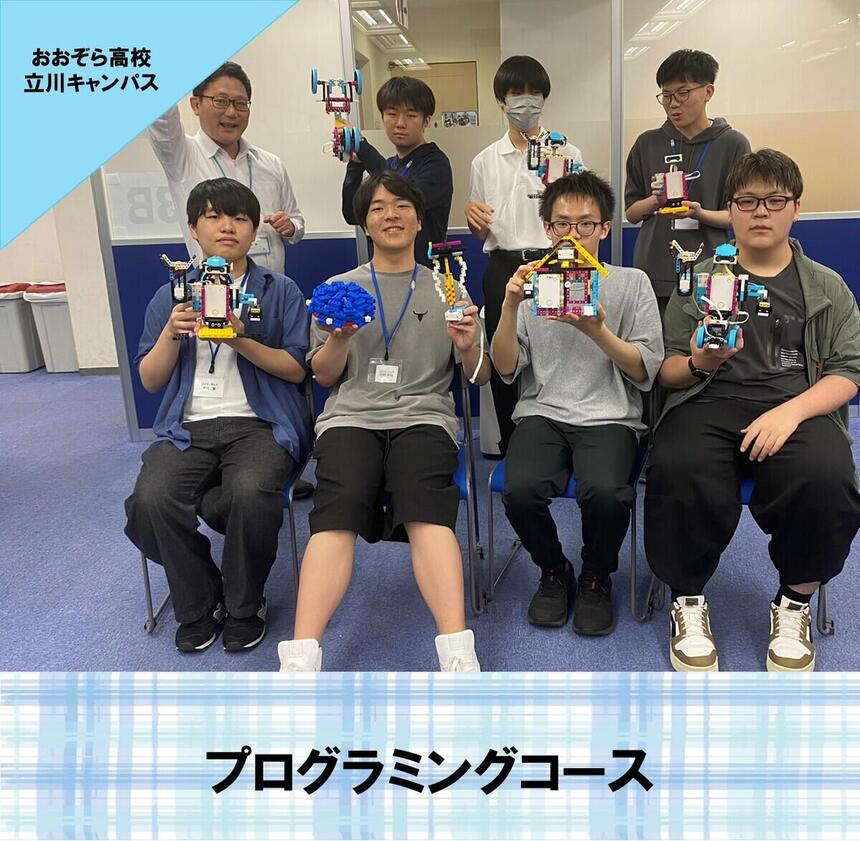 プログラミングコースの生徒が自分たちで作成をしたロボットを持って笑っている写真