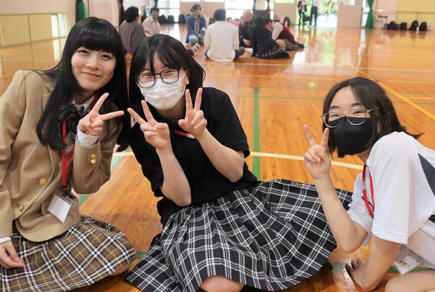 イベントに参加をした新入生3名が体育館で笑顔でピースサインをして写っている写真