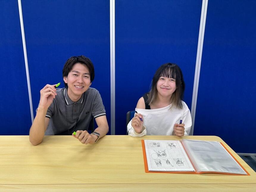 コーチと生徒がマンガイラストコースで使うペンやファイルを持っている様子