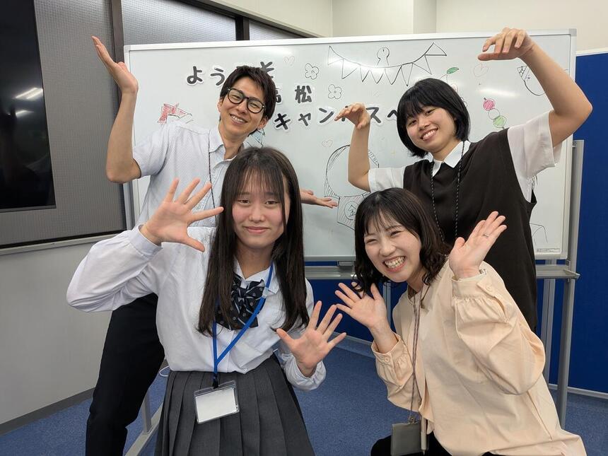 2年生の在校生と3人のコーチがホワイトボード前で笑顔で写っている写真