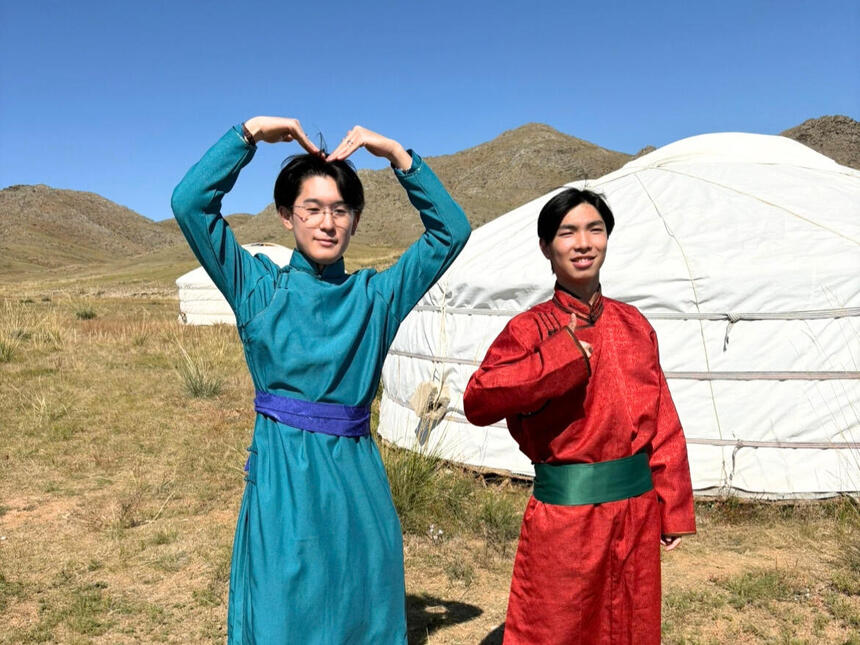 2人の生徒がモンゴルの民族衣装を着て笑顔でポーズを決めている様子