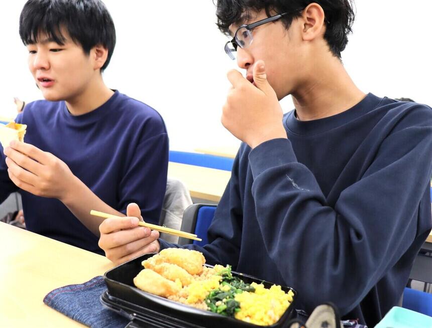 お昼休みに教室で1年生の生徒が楽しくお弁当を食べている様子。