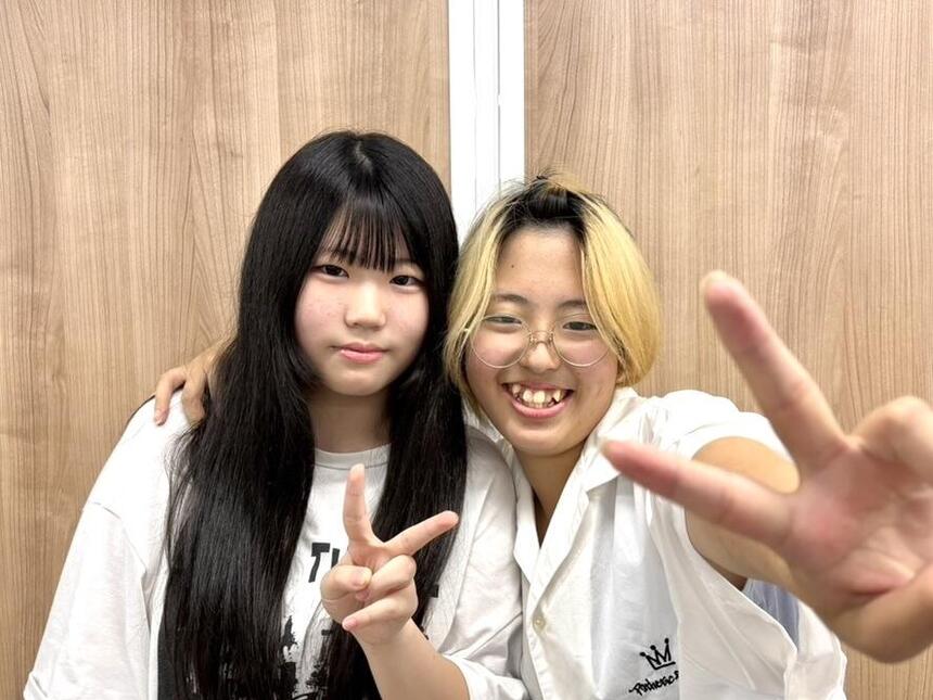 女子生徒２人肩を組みながら、こちらに向けて笑顔でピースサインを向けている画像