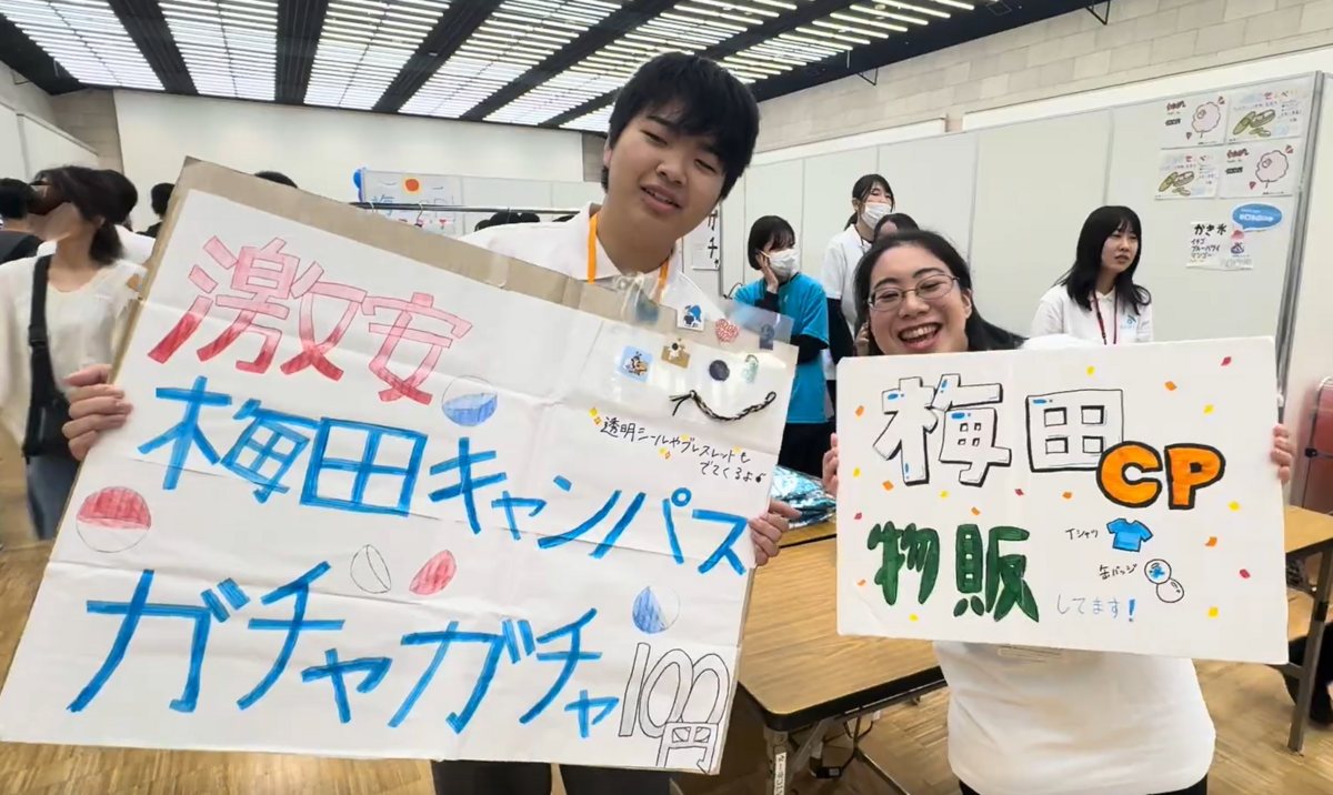 お手製の看板を掲げて元気いっぱいに宣伝する生徒