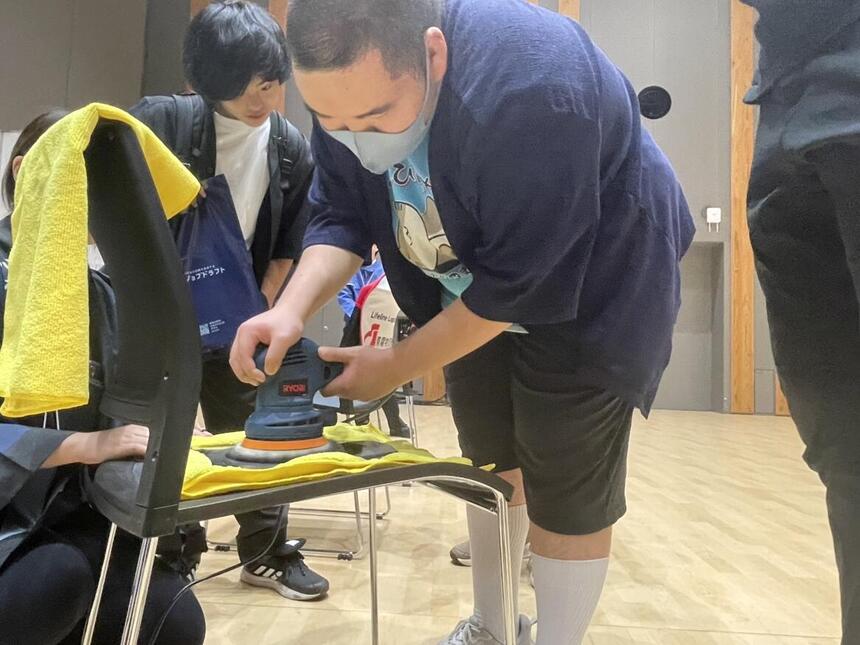 金属加工の体験ブースで、生徒が専用の道具を使いながら鉄板を磨いています。