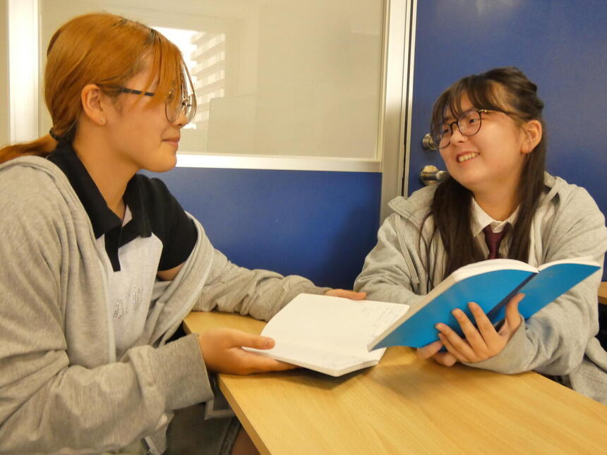 キャンパスでみらいノート®を見せ合いながら女子生徒2人が談笑しています。