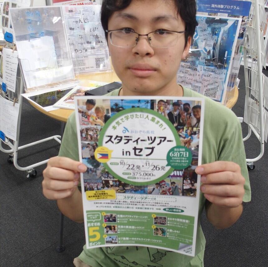 キャンパスで生徒が海外体験のチラシを手に写っています。