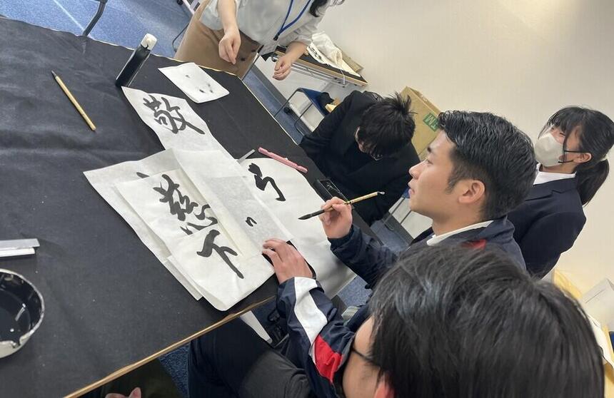 生徒とコーチでキャンパス目標の書初めをしている様子