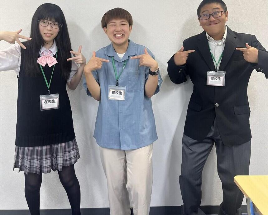 制服や私服を来た生徒たちが自分の服装を指し示しながら笑顔で写る写真