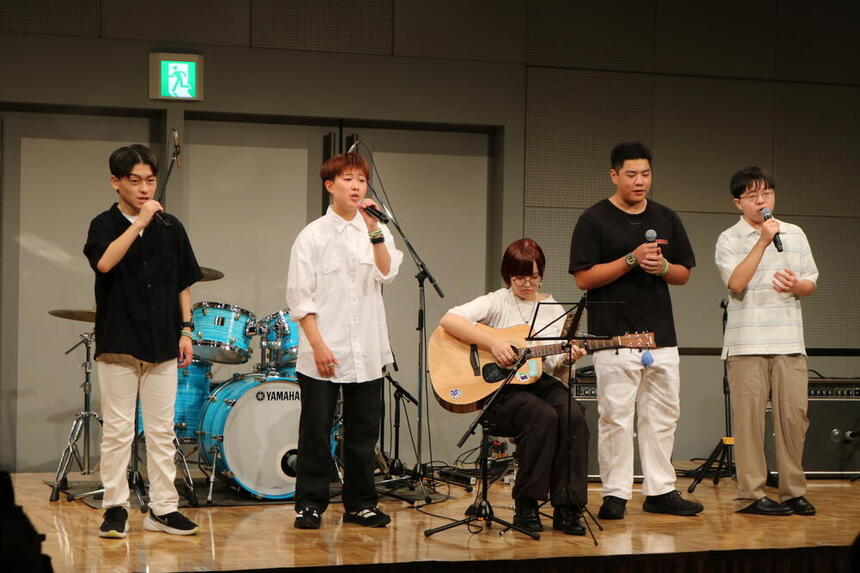 和歌山キャンパスの生徒がおおぞらFESのステージで歌を歌い、ギターを演奏する様子