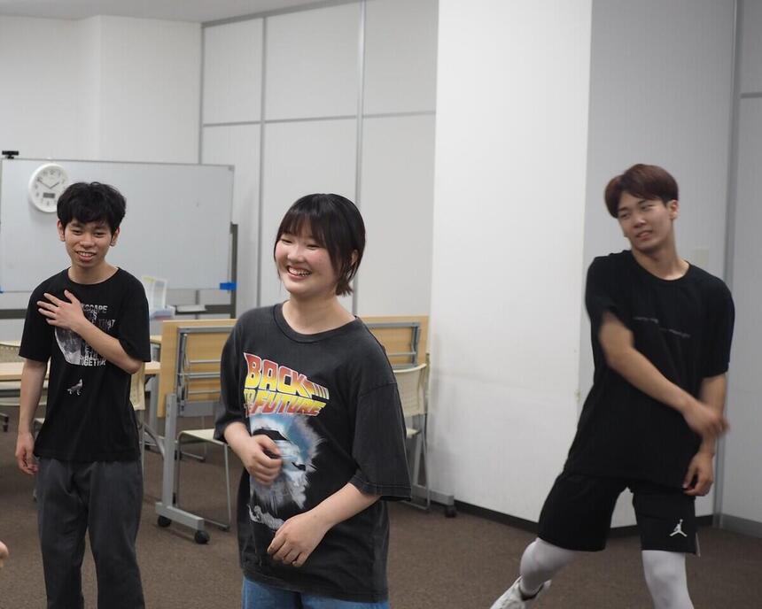 レッスン中の振付を音楽に合わせる中でふと笑顔がこぼれる男子高校生と女子高校生