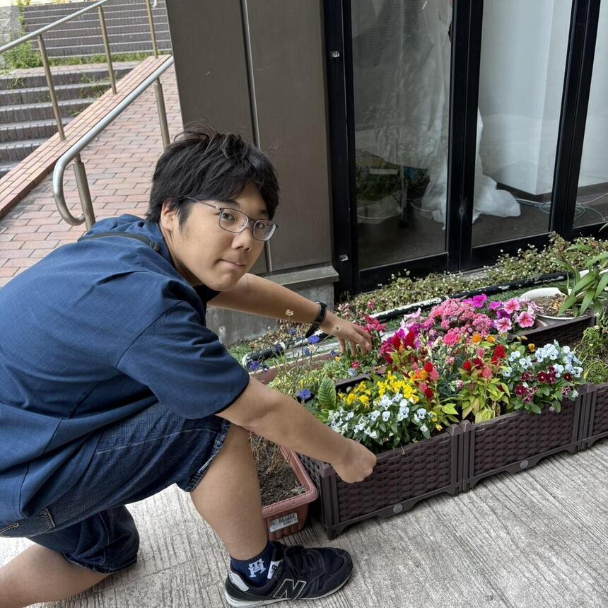 男子生徒が横浜キャンパスの玄関前で花壇を整備している様子