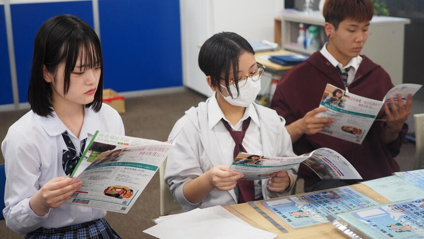 進路ガイダンスである専門学校の説明を熱心に聞いている高校生
