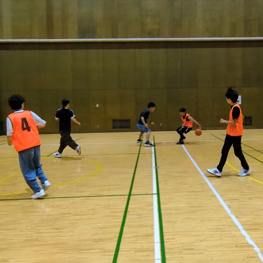体育館でバスケットボールの試合を楽しむ男子高校生たち
