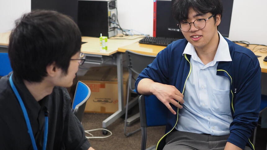 教室内で男性スタッフと面談をする男子生徒