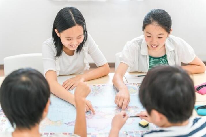 4人の子どもが地図を囲みながら笑顔でグループワークをしている
