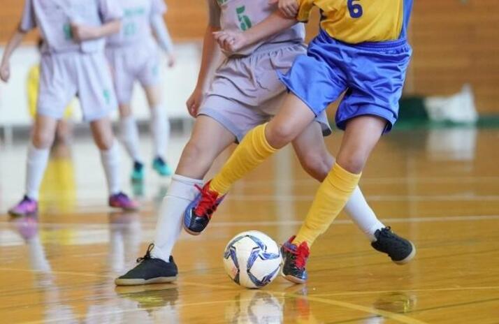 体育館で男子学生がサッカーの試合を行っている様子