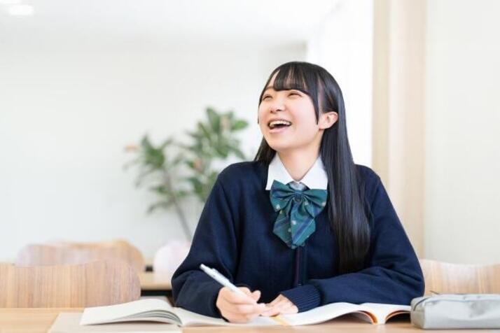 制服を着た女子生徒が笑顔で話を聞いている様子