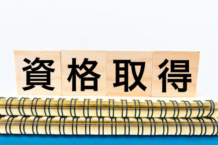 ノートの上に資格取得と書かれたブロックが置かれている画像
